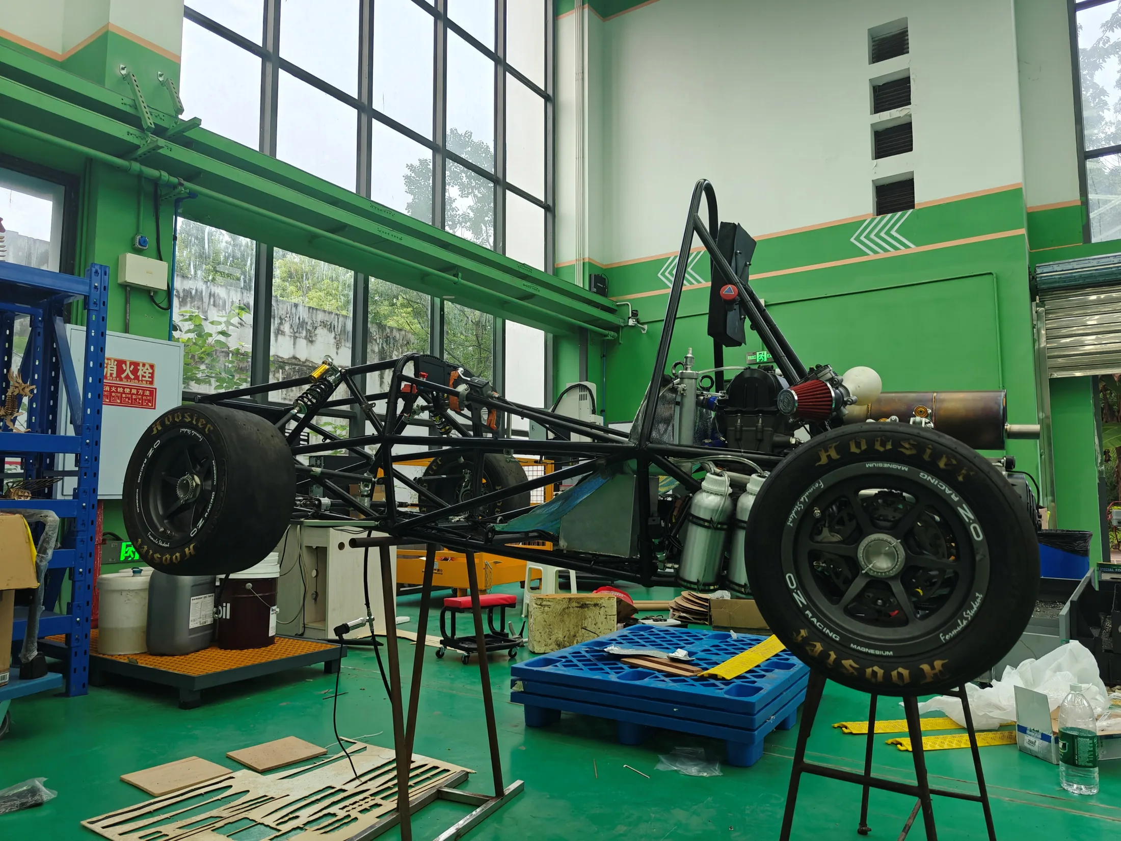 车间内正在装配的方程式赛车，展示车架、悬架和动力系统